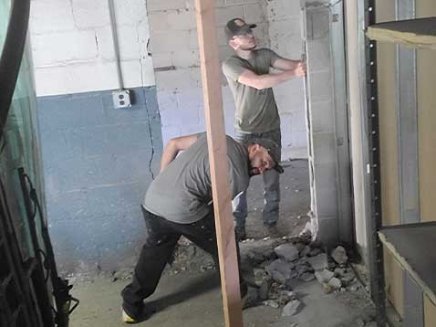 Two men working construction in brick building